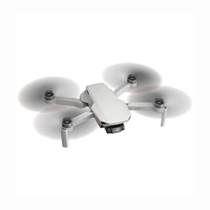 future tech gadgets Canada. cutting edge electronics online Canada. DJI Mini 4K Quadcopter Drone with Camera & Controller. Gallery image 3. The drone is positioned at a slight angle, showcasing its sleek, compact design against a seamless white background. Its body is primarily a matte white, with four propellers that appear to be in motion, creating a soft blur effect. The front features a small camera lens and the text "MINI 2K" is visible on the body.