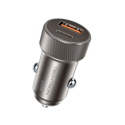 smart tech store Canada. premium tech accessories Canada. Techtron C-857 33W USB-C and USB-A Car Charger. Gallery image 1. The image features a compact car charger positioned at a slight angle, showcasing its top and side. The charger has a sleek, metallic gray finish with a textured, ribbed edge for grip. Two charging ports are visible on the top: one USB-A and one USB-C, both highlighted against the smooth surface. The background is a seamless white, emphasizing the product's design.