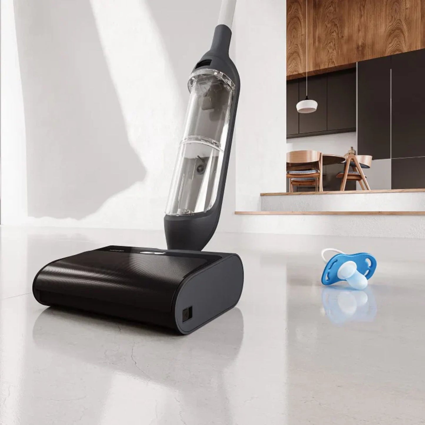future tech gadgets Canada. smart tech store Canada. HiZero F300 All-in-One Bionic Floor Cleaner. Gallery image 2. A sleek, black vacuum cleaner is positioned at an angle in the foreground, with its transparent dust container prominently displayed. The vacuum rests on a smooth, light-colored floor, reflecting soft light that highlights its glossy finish. In the background, a modern kitchen is visible, featuring wooden cabinetry and a dining area with chairs.