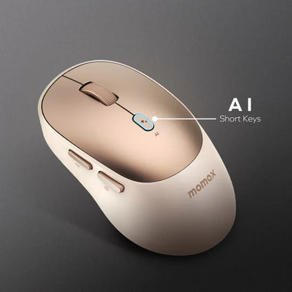 future tech gadgets Canada. smart tech store Canada. Momax 1-Folio A.I. Mouse. Gallery image 4. The image shows a sleek, ergonomic wireless mouse positioned at an angle against a dark grey background. The mouse features a glossy gold top with a matte cream-colored body. A prominent blue button labeled "AI" is located near the center, accompanied by two smaller buttons on the side. The brand name "momax" is subtly embossed in gold on the lower part of the mouse.