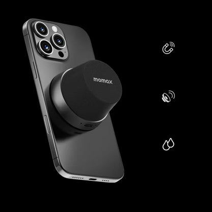 future tech gadgets Canada. premium tech accessories Canada. Momax 1-Vibe Go Magnetic Wireless Speaker. Gallery image 1. A sleek black smartphone is positioned at an angle, showcasing its glossy finish and three rear cameras. Attached to the back is a round, black speaker with a textured surface, prominently displaying the "momax" logo on top. The background is solid black, enhancing the product's modern aesthetic.
