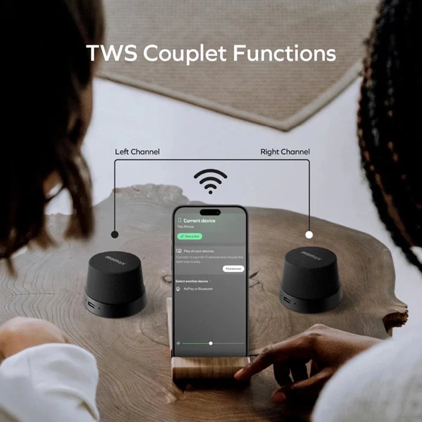 future tech gadgets Canada. premium tech accessories Canada. Momax 1-Vibe Go Magnetic Wireless Speaker. Gallery image 11. A smartphone is positioned centrally on a wooden surface, displaying a green interface with options for connecting devices. Two small black speakers are placed on either side of the phone, labeled "Left Channel" and "Right Channel." The lighting is soft, creating a warm atmosphere, while the background features a textured wall and a woven mat.