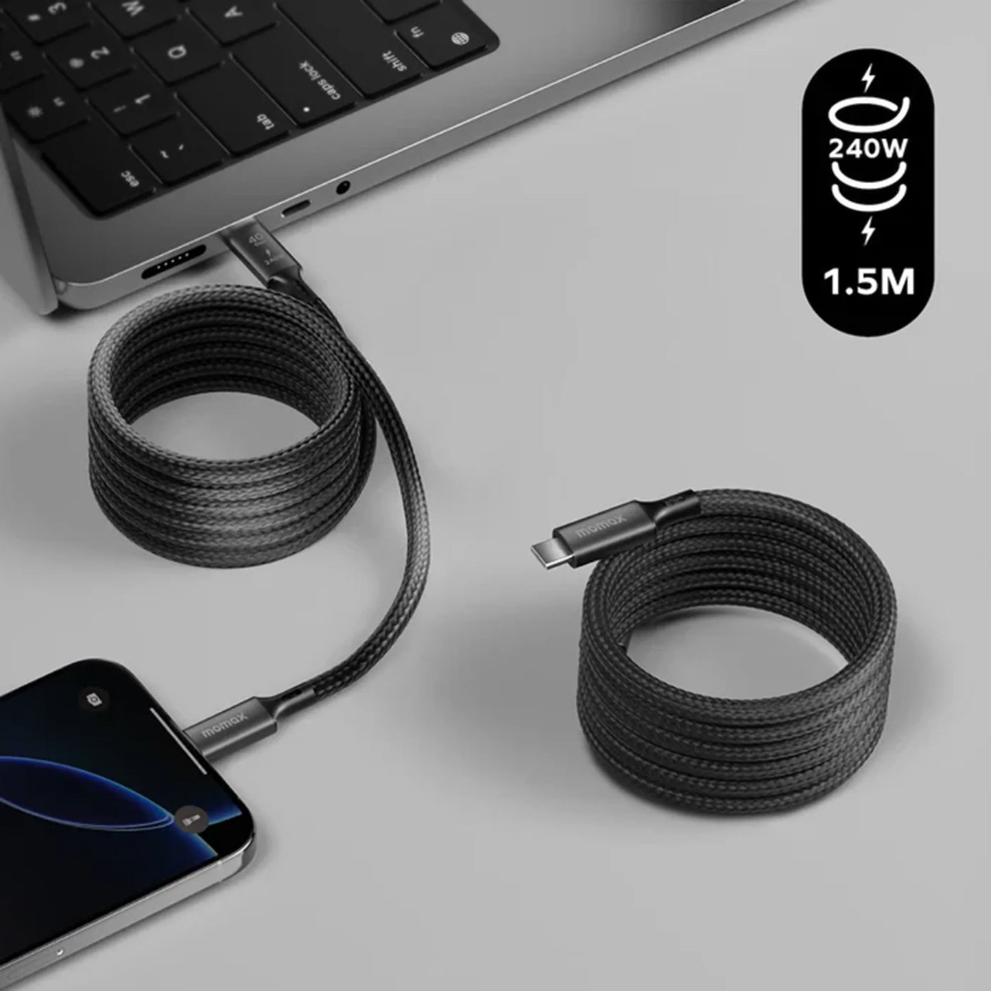 next gen electronics shop. buy electronics online Canada. Momax Mag.Link 240W Usb-C To Usb-C Usb 4 40Gbps Magnetic Cable 1.5M. Gallery image 3. A black braided charging cable is coiled on a light grey surface, with one end plugged into a smartphone and the other end extending towards a laptop. The laptop's keyboard is partially visible in the background, showcasing a sleek design.