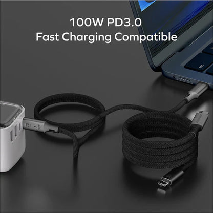 smart tech store Canada. next gen electronics shop. Momax Mag Link 100W USB-C to USB-C USB 3.2 Gen 2x2 Magnetic Cable 1M. Gallery image 4. A black braided USB-C charging cable is prominently displayed on a smooth, dark surface, with one end connected to a white charging block and the other plugged into a laptop. The cable is coiled neatly, showcasing its flexibility and texture. Above the cable, bold white text reads "100W PD3.0 Fast Charging Compatible," indicating its capabilities.