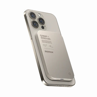 future tech gadgets Canada. premium tech accessories Canada. Momax Q.Mag X 5000mAh Wireless Battery Pack. Gallery image 7. The image features a sleek, silver smartphone positioned at a slight angle, showcasing its rear side. Attached to the back is a magnetic battery pack labeled "Q.MAG X 5000 mAh" in a matte finish, with the brand name "momax" visible. The background is a seamless white, enhancing the product's modern aesthetic.