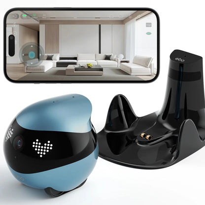 smart tech store Canada. premium tech accessories Canada. Enabot Ebo Air 2 Companion Robot. Gallery image 2. A small, round robotic device in a soft blue color is positioned in the foreground, featuring a glossy black band around its middle with two heart-shaped LED lights. It has a camera lens on the front and rolls on small wheels. Behind it, a sleek black charging dock with two gold connectors is visible.