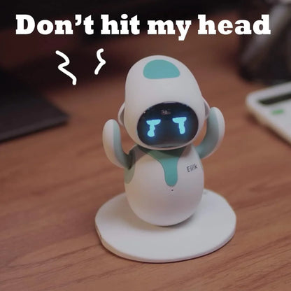smart tech store Canada. premium tech accessories Canada. Eilik Desktop Companion AI Robot. Gallery image 4. A small, cartoonish robot stands on a circular white base, centered in the frame. Its body is predominantly white with teal accents on the head and arms. The robot has a digital face displaying blue tears and a frowning expression, with the text "Don't hit my head" prominently above it in bold, white letters.