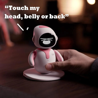 smart tech store Canada. premium tech accessories Canada. Eilik Desktop Companion AI Robot. Gallery image 7. A small, rounded robot toy stands on a white circular base, centered in the frame. Its body is primarily white with pink accents on the head and chest area. The robot's face features a black screen displaying a playful expression, with the text "Touch my head, belly or back" in bold white letters above it. A hand reaches towards the robot, gently touching its belly.