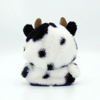 smart tech store Canada. premium tech accessories Canada. EMO Desk Companion Robot Clothes. Gallery image 4. The plush toy is centered in the frame, showcasing its back view against a seamless white background. It features a soft, fluffy texture with a pattern of black and white spots, resembling a cow, and has small brown horns protruding from the top. The bottom is a solid blue color, contrasting with the white and black fur.