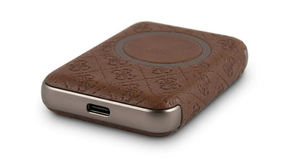 future tech gadgets Canada. premium tech accessories Canada. Guess BP MagSafe Case + PWB 5000mAh 4G. Gallery image 6. The product is a sleek, rectangular wireless charger, positioned at a slight angle in the frame. The surface features a rich brown leather-like texture with a quilted pattern, accented by a smooth, circular area in the center. The edges are metallic and have a brushed finish, with a visible USB-C port on one side.