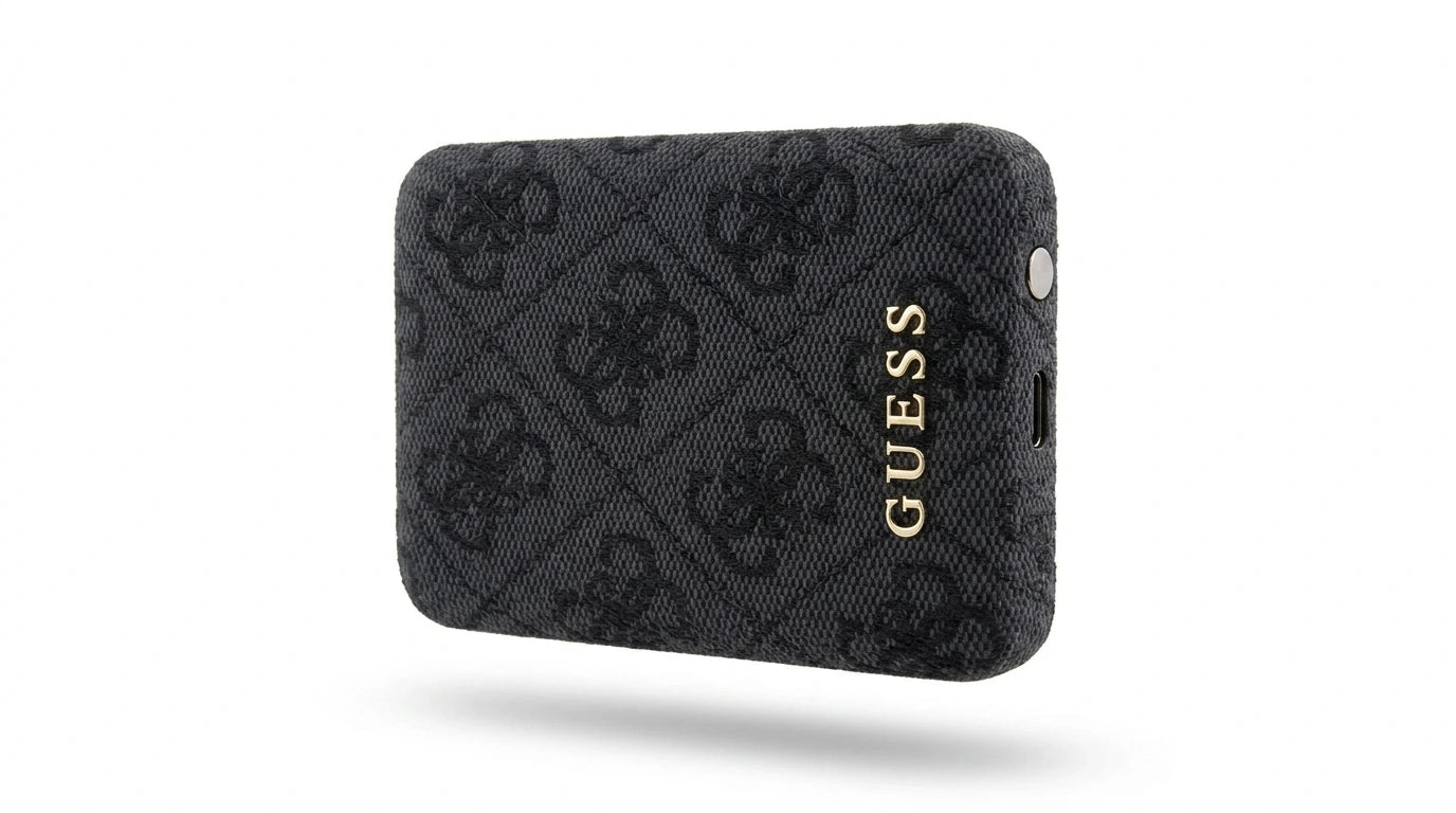 future tech gadgets Canada. premium tech accessories Canada. Guess BP MagSafe Case + PWB 5000mAh 4G. Gallery image 7. The product is a black wallet with a textured surface featuring a subtle pattern of interlocking logos. It is positioned at a slight angle, showcasing its depth and the glossy gold "GUESS" logo on the front. The background is a clean, seamless white, enhancing the wallet's design. The lighting is soft, highlighting the texture of the fabric while casting minimal shadows.