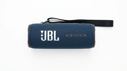 future tech gadgets Canada. smart tech store Canada. JBL Flip 7 Portable waterproof and drop-proof speaker. Gallery image 4. The image shows a portable Bluetooth speaker positioned centrally against a seamless white background. The speaker has a textured navy blue fabric exterior with a matte finish, and the prominent white "JBL" logo is displayed on the front. On the side, there are several buttons, including a power button and volume controls, all in a darker shade of blue.