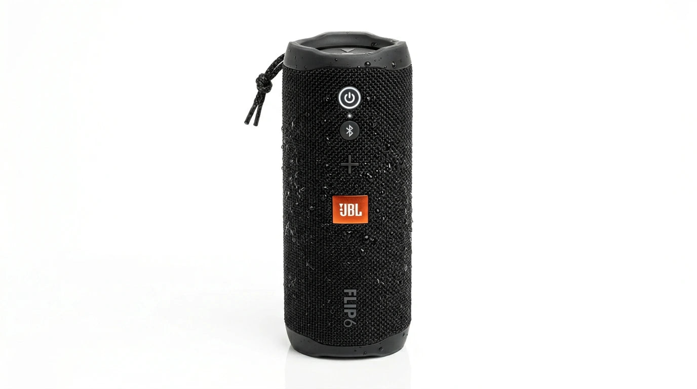future tech gadgets Canada. smart tech store Canada. JBL Flip 7 Portable waterproof and drop-proof speaker. Gallery image 5. The speaker is positioned centrally against a seamless white background, showcasing its cylindrical shape. It features a textured black fabric exterior with visible water droplets, indicating its water-resistant design. The front displays three buttons: a power button, a Bluetooth pairing button, and a volume control, all in a contrasting color.