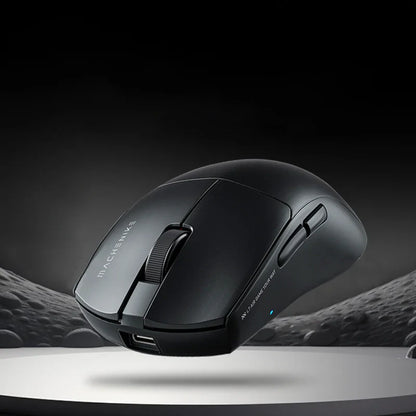 future tech gadgets Canada. premium tech accessories Canada. Machenike L7 Air Tri-Mode Mouse. Gallery image 2. The image features a sleek, black gaming mouse positioned at a slight angle, showcasing its ergonomic design. It is set against a dark, gradient background that enhances its contours and details. The mouse has a textured scroll wheel and two side buttons, with a small blue LED indicator visible near the base.