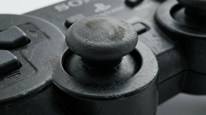 future tech gadgets Canada. premium tech accessories Canada. Machenike G5 Pro V2 Tri-Mode Controller. Gallery image 5. The image features a close-up view of a black gaming controller, focusing on the textured joystick. The joystick is slightly worn, showing signs of use with a few scratches and smudges. Surrounding the joystick are several buttons and a directional pad, all in a matte black finish. The background is softly blurred, emphasizing the controller's details.