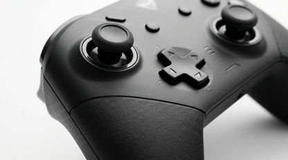 future tech gadgets Canada. premium tech accessories Canada. Machenike G5 Pro V2 Tri-Mode Controller. Gallery image 9. The image features a close-up view of a black gaming controller, angled slightly to the right. The controller's textured grip is prominent, with two analog sticks positioned on the left and right, each topped with a knurled surface for better grip. The central directional pad and four action buttons are visible, along with several additional buttons and indicators.