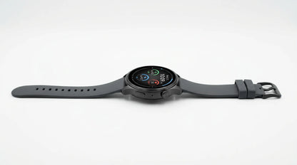 smart tech store Canada. premium tech accessories Canada. Techtron Aurafit AM28 Smart Watch. Gallery image 10. The smartwatch is displayed horizontally against a seamless white background, showcasing its sleek design. The round face features a vibrant digital display with colorful icons indicating time and fitness metrics. The body is matte black, complemented by a matching silicone strap that has multiple adjustment holes and a secure buckle.