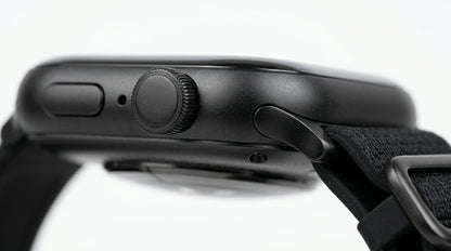 smart tech store Canada. premium tech accessories Canada. Techtron SWH18 (T52 / T67) Smart Watch. Gallery image 5. The image shows a close-up view of a black smartwatch, angled slightly to the right. The watch features a textured black strap and a round, glossy watch face. Prominent on the side are a circular crown and a button, both in a matte finish, with a small microphone hole nearby. The background is a seamless white, enhancing the watch's sleek design.