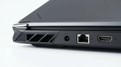 future tech gadgets Canada. smart tech store Canada. ThundeRobot R16 i9 Gaming Laptop. Gallery image 9. The image shows a close-up view of the left side of a laptop, angled slightly to reveal various ports and vents. The surface is a smooth, light grey, providing a clean backdrop. The laptop's body is predominantly matte black with glossy accents, particularly around the edges. Visible ports include a USB port, a power input, an Ethernet port, and an HDMI port, all neatly arranged.